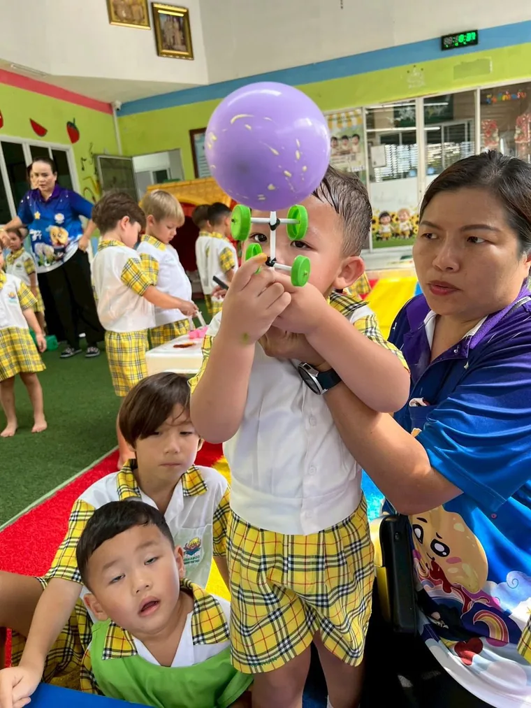 คุณครูช่วยเด็กทดลองกับลูกโป่งสีม่วง